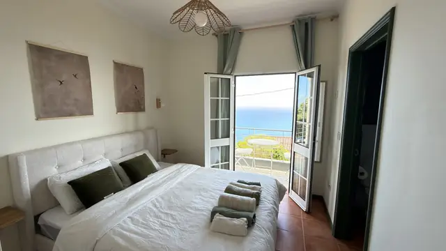 A bright bedroom with a French door to the ocean view