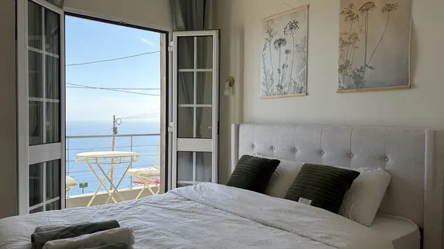 A bedroom with French doors open to a terrace and the ocean